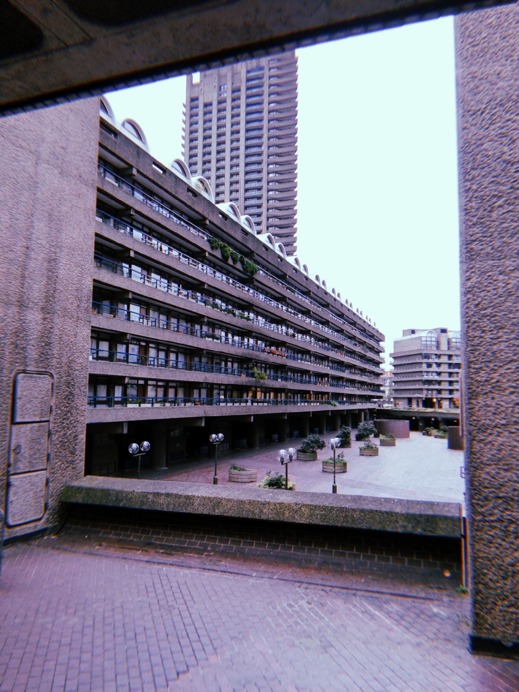 A modern, brutalist-style architectural complex features a large, geometric building with rows of apartments and a courtyard.